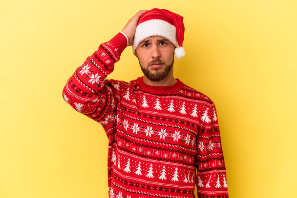 Junge kaukasische Mann feiert Weihnachten isoliert auf gelbem Hintergrund schockiert, sie hat sich an wichtiges Treffen erinnert. - Foto, Bild
