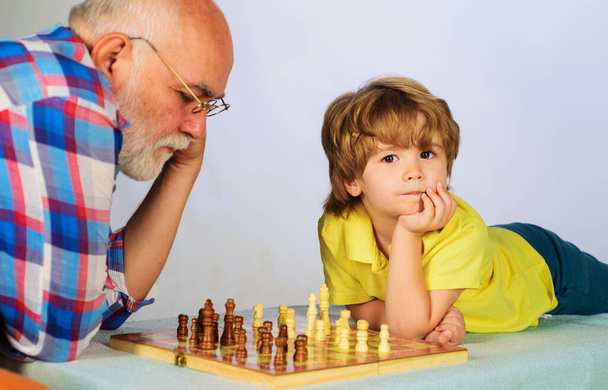 Παππού και εγγονός παίζουν σκάκι. Ο παππούς μαθαίνει στο εγγόνι του να παίζει σκάκι. Ματ.. - Φωτογραφία, εικόνα