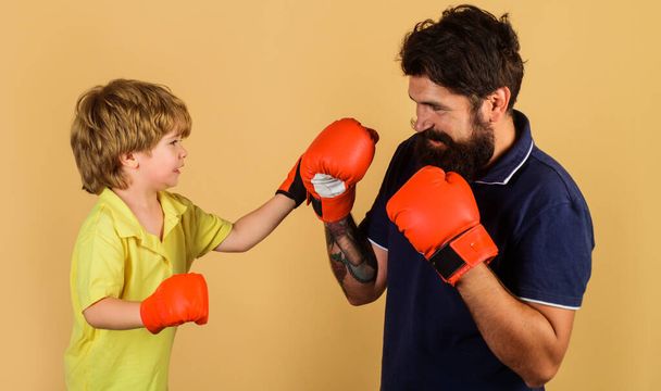 Vader en zoon tijdens de bokstraining. Kind jongen bokser in handschoenen oefenen stoten met coach. - Foto, afbeelding