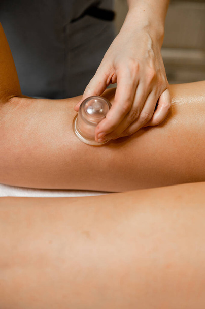 Massage with vacuum cups on the leg of a girl close-up. Vacuum therapy with massage jars. - Photo, Image