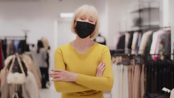 Úspěšný zralý středního věku žena prodejce konzultant oblečení majitel obchodu v lékařské masky stojí v obchoďáku sebevědomě při pohledu na kameru pózování s pažemi přes hrudník malé podnikání koncept - Záběry, video