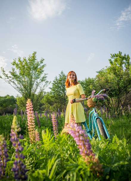 Young teen girl with vintage bike in flowered meadow - Fotó, kép