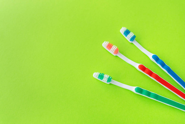 Veelkleurige tandenborstels op een groene achtergrond, het concept van tandverzorging en mondhygiëne. Plaats voor een opschrift - Foto, afbeelding