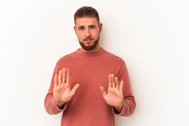Young caucasian man with diastema isolated on white background rejecting someone showing a gesture of disgust. - Photo, Image