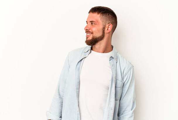 Jonge blanke man met diastema geïsoleerd op witte achtergrond ontspannen en gelukkig lachen, nek gestrekt tonen tanden. - Foto, afbeelding