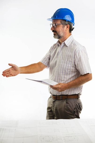 Чоловік у шоломі інженера тримає одну руку і контракт в іншому
. - Фото, зображення