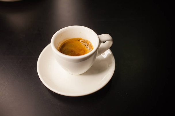 Świeżo zaparzona kawa podawana w filiżance na ciemnym tle - Zdjęcie, obraz