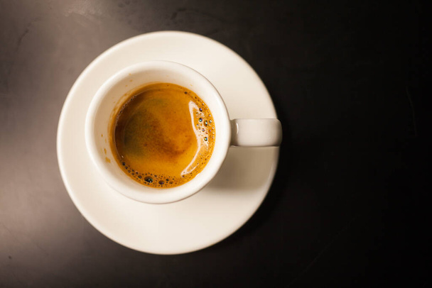 濃い色の背景のカップで提供される新鮮なコーヒー - 写真・画像