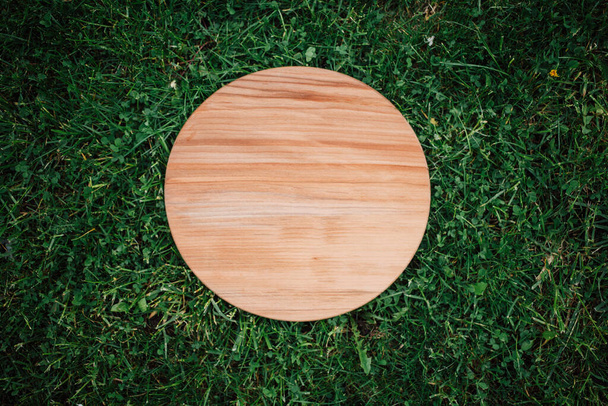 Tablero redondo de madera sobre fondo de hierba verde - Foto, imagen