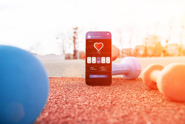 Podanie na siłownię. Ekran smartfona ze zdrowiem fitness lub sportową aplikacją mobilną na tle hantli. Program fitness online - Zdjęcie, obraz