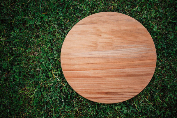 Round wooden board on green grass background - Photo, Image