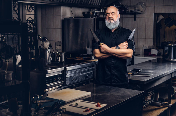 Vecchio chef con utensili da cucina al chiuso la sua cucina - Foto, immagini