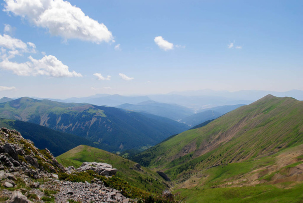 Гірський ландшафт довгих зелених гірських хребтів з ясним блакитним небом з декількома хмарами
. - Фото, зображення
