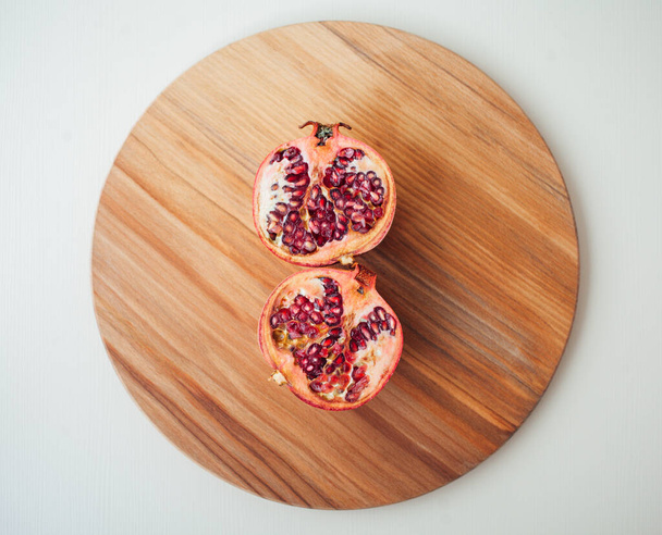 Pomegranate fruit on a round wooden board, closeup shot  - 写真・画像