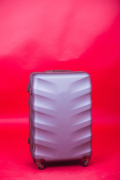Viaggio valigia viola su sfondo rosso - Foto, immagini