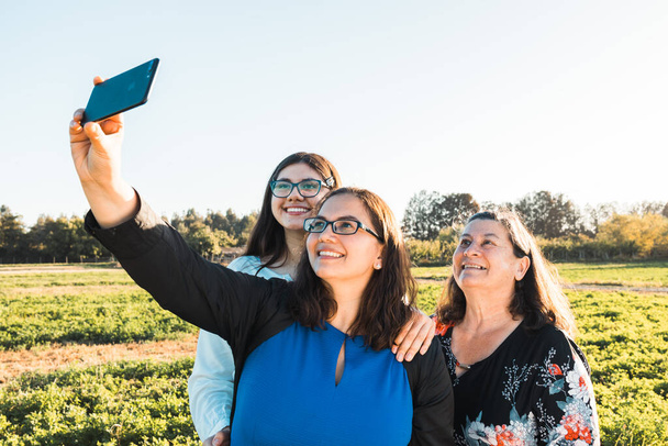Familia Femenina tomando una selfie en el campo, en un día soleado por la tarde. Día de las madres. - Foto, imagen