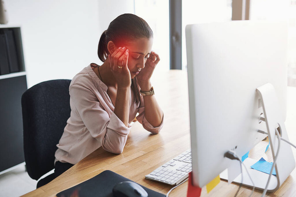 El estrés y la ansiedad del trabajo pueden desencadenar fuertes dolores de cabeza. Fotografía de una joven empresaria que sufre de dolor de cabeza mientras trabaja en una oficina. - Foto, Imagen