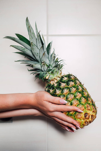 Nainen kädet tilalla kypsä ananas valkoisella pohjalla
 - Valokuva, kuva