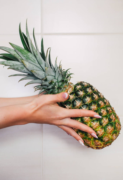Nainen kädet tilalla kypsä ananas valkoisella pohjalla
 - Valokuva, kuva