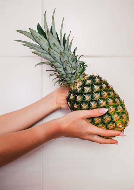 Female hands holding ripe pineapple on a white background - Φωτογραφία, εικόνα