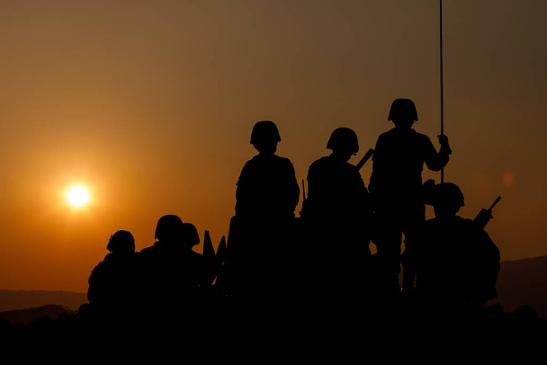 silhouette group of special forces sodiers standing and sit on tank with over the sunset background,  - Zdjęcie, obraz
