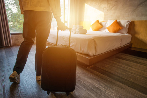 Otele giriş yaptıktan sonra bavulunu otel odasına çeken bir turist fotoğrafı. Seyahat ve tatil kavramı. - Fotoğraf, Görsel