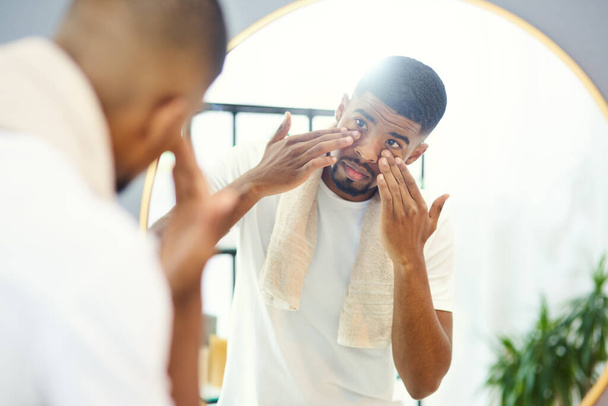 This face cream was well recommended. Young man applying face product in his bathroom mirror. - Foto, Imagen