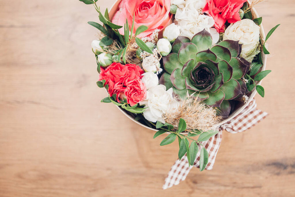 Schöne Blumenarrangements in einer Hutschachtel, Holzhintergrund  - Foto, Bild
