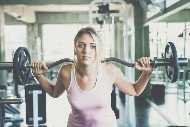 Beautiful smart sport women lifting barbell in fitness gym sport concept - Valokuva, kuva