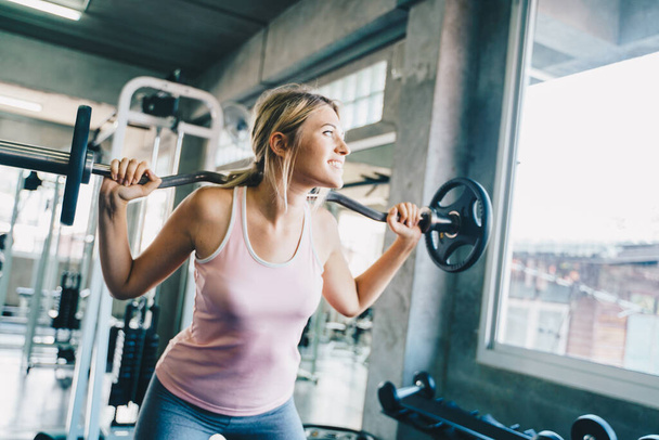 Beautiful smart sport women lifting barbell in fitness gym sport concept - Фото, зображення
