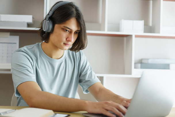Distance education concept, Teen boy wear headphone to lesson class online and type chat in skype. - Photo, Image