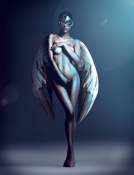 Dangerously desirable. Studio shot of a naked woman with wings and a mask. - Foto, immagini