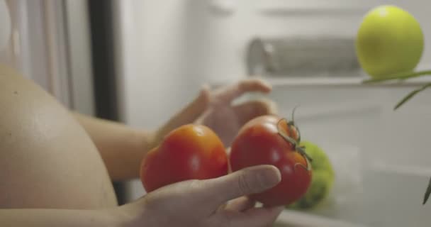 Raskaana oleva nainen päättää syödä tomaatteja päivälliseksi. Terveellistä ruokaa raskaana oleville naisille. - Materiaali, video