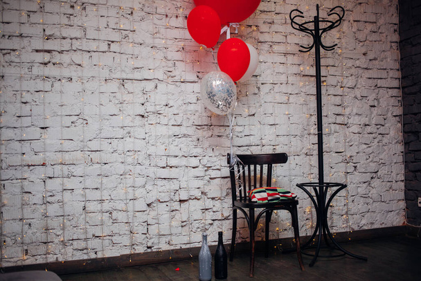 Holzsessel und große bunte Luftballons auf weißem Backstein-Hintergrund  - Foto, Bild