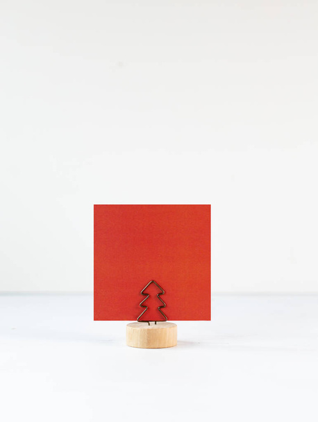 Porta note con clip a forma di albero di Natale e cartolina bianca su sfondo bianco. Layout di scrittura dei messaggi. - Foto, immagini