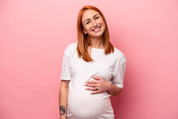 Young caucasian pregnant woman isolated on pink background happy, smiling and cheerful. - Foto, Imagem