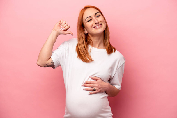 Young caucasian pregnant woman isolated on pink background feels proud and self confident, example to follow. - Photo, Image