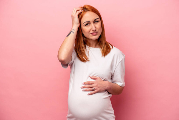 Νεαρή καυκάσια έγκυος γυναίκα απομονωμένη σε ροζ φόντο σοκαρισμένη, θυμήθηκε σημαντική συνάντηση. - Φωτογραφία, εικόνα