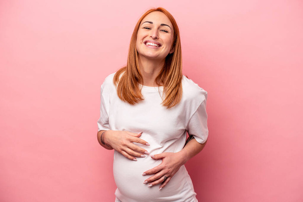 Jovem mulher grávida caucasiana isolado no fundo rosa rindo e se divertindo. - Foto, Imagem