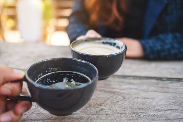 Imagen de cerca de dos personas tazas de café tintineo en la mesa de madera  - Foto, imagen