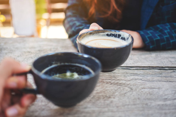 Image rapprochée de deux personnes cliquetis tasses à café sur table en bois  - Photo, image