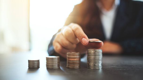 Podnikatelka drží a stohuje mince na stole - Fotografie, Obrázek