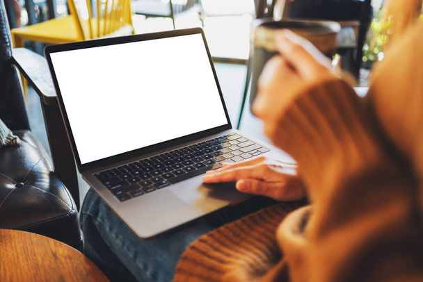 Mockup kép egy nő használja és megérinti a laptop érintőpad üres fehér asztali képernyő kávézás közben - Fotó, kép