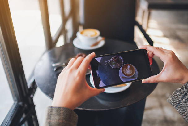 Una mujer que usa el teléfono móvil para tomar una foto de café y merienda antes de comer - Foto, imagen