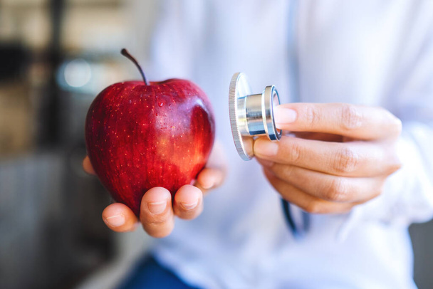 Zbliżenie obrazu lekarza używającego stetoskopu do zbadania czerwonego jabłka - Zdjęcie, obraz