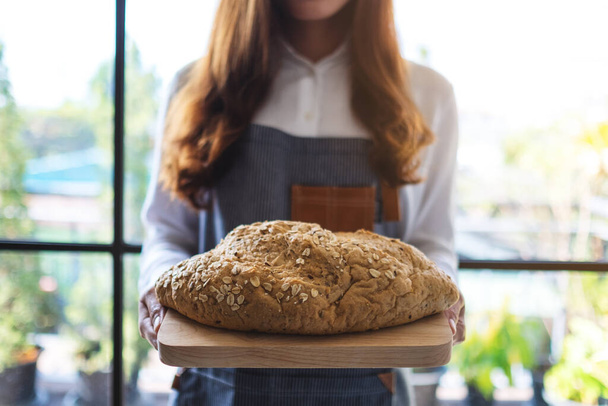 Uma garçonete segurando e servindo um pão de grão integral - Foto, Imagem