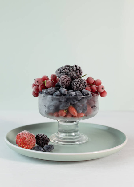A mix of frozen berries in a transparent bowl. Berries are rich in vitamin C, home freezing, harvesting for the winter. - Photo, Image