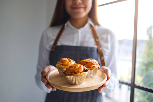 Μια σερβιτόρα που κρατάει ένα ξύλινο πιάτο με σταφίδες Δανέζικα  - Φωτογραφία, εικόνα