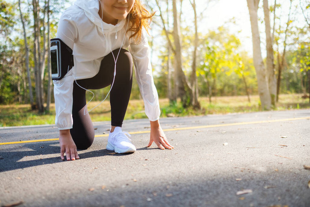 Женщина-атлет на стартовой точке, готовится к пробежке в городском парке утром - Фото, изображение