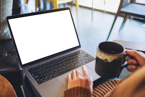 Mockup obrazu kobiety używającej i dotykając na laptopie touchpad z pustym białym ekranem pulpitu podczas picia kawy - Zdjęcie, obraz